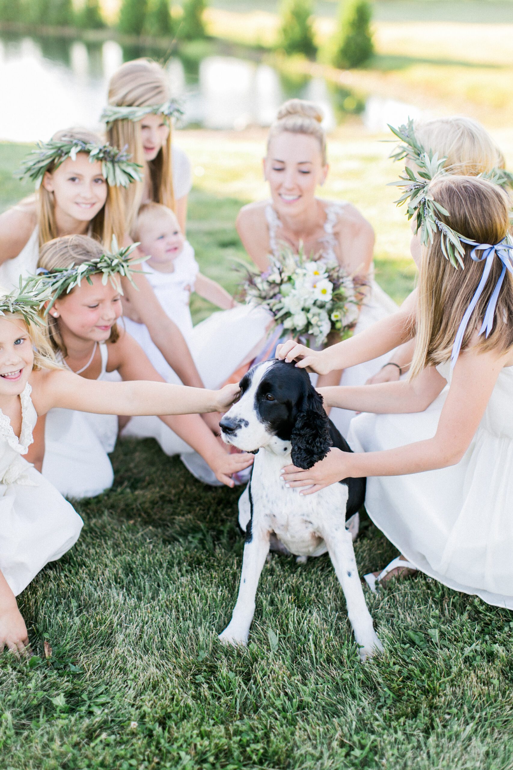 A bride and her flower girls all pet a sweet dog