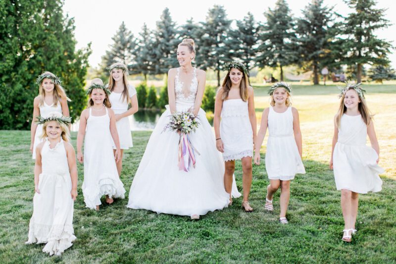 A bride walks through a mowed lawn with her flower girls