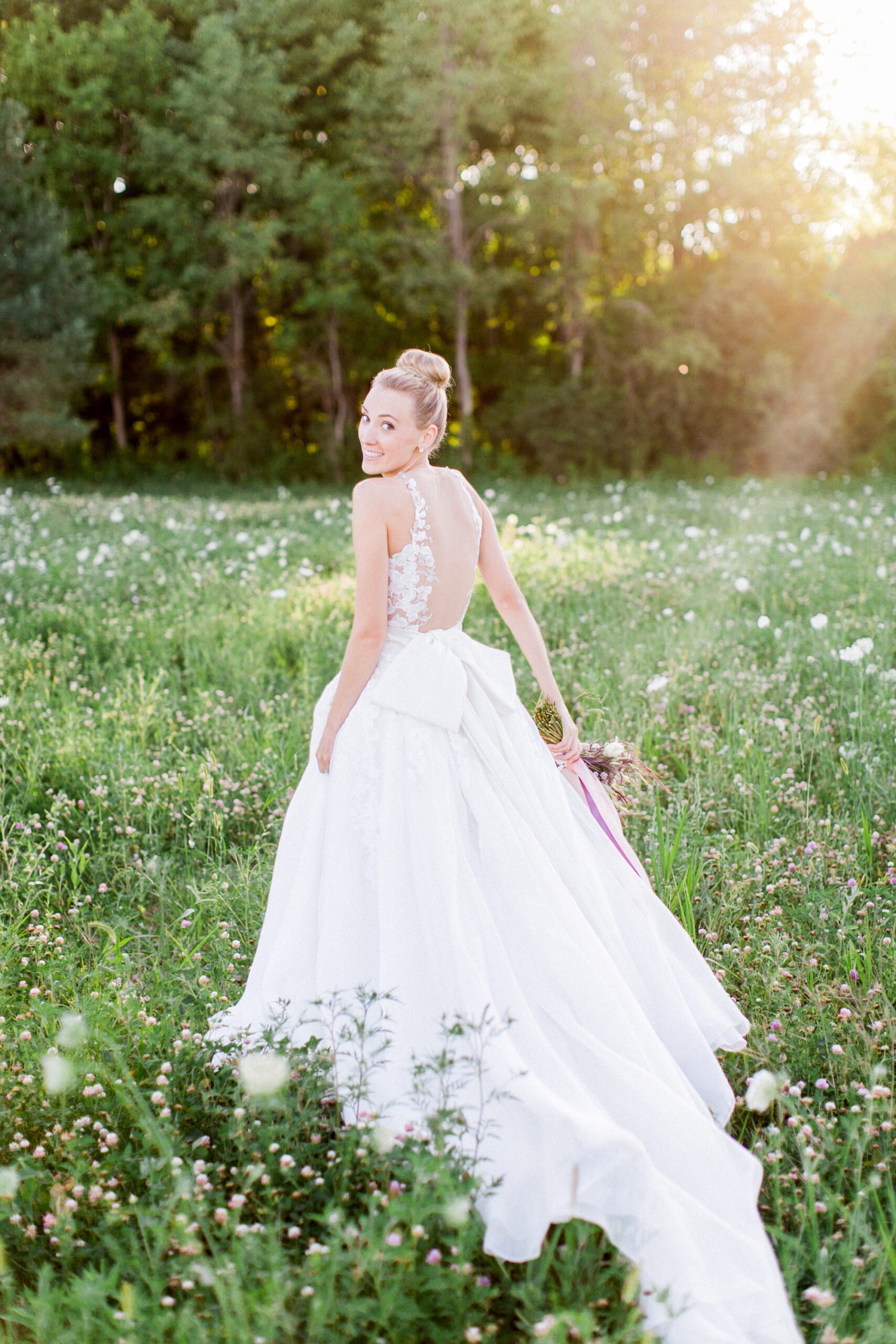 A bride walks through a field of wild flowers for wedding photography
