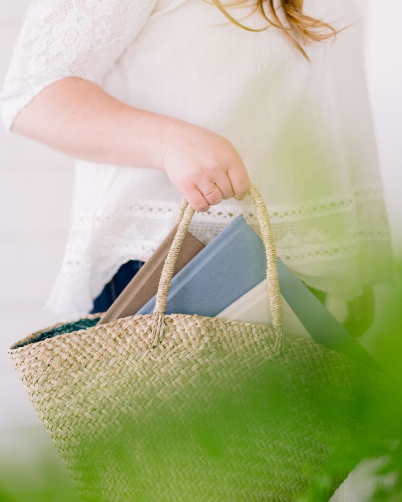 A woman holds a wicker bag with photo albums inside