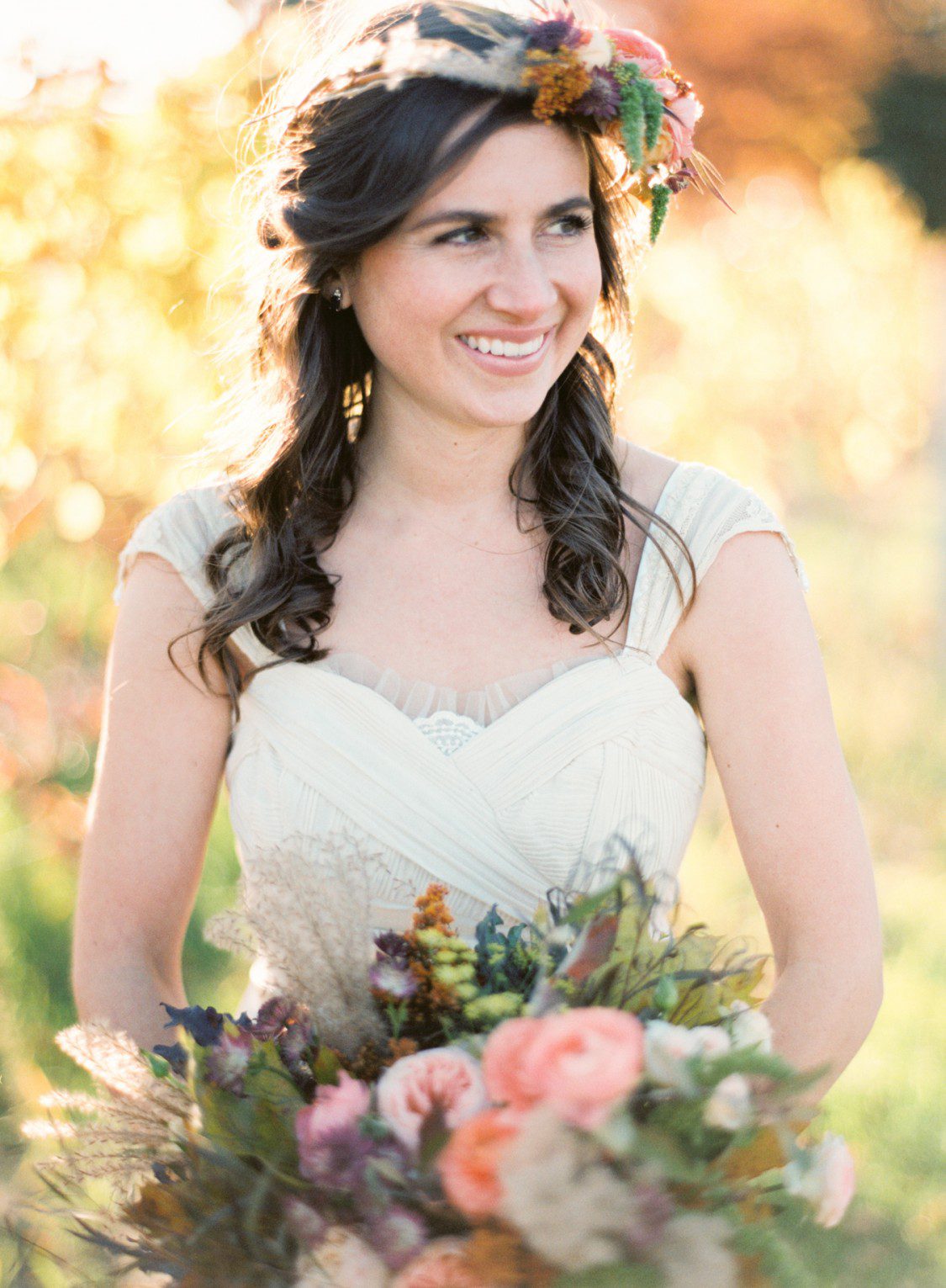 A bride holds a fall bouquet and smiles for Published northern michigan photographer