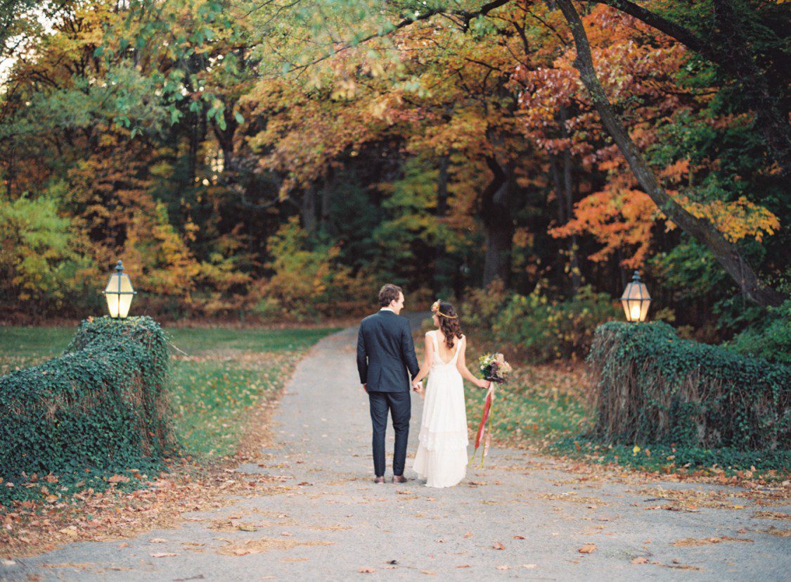 a bride and groom walk beside an ivy wall