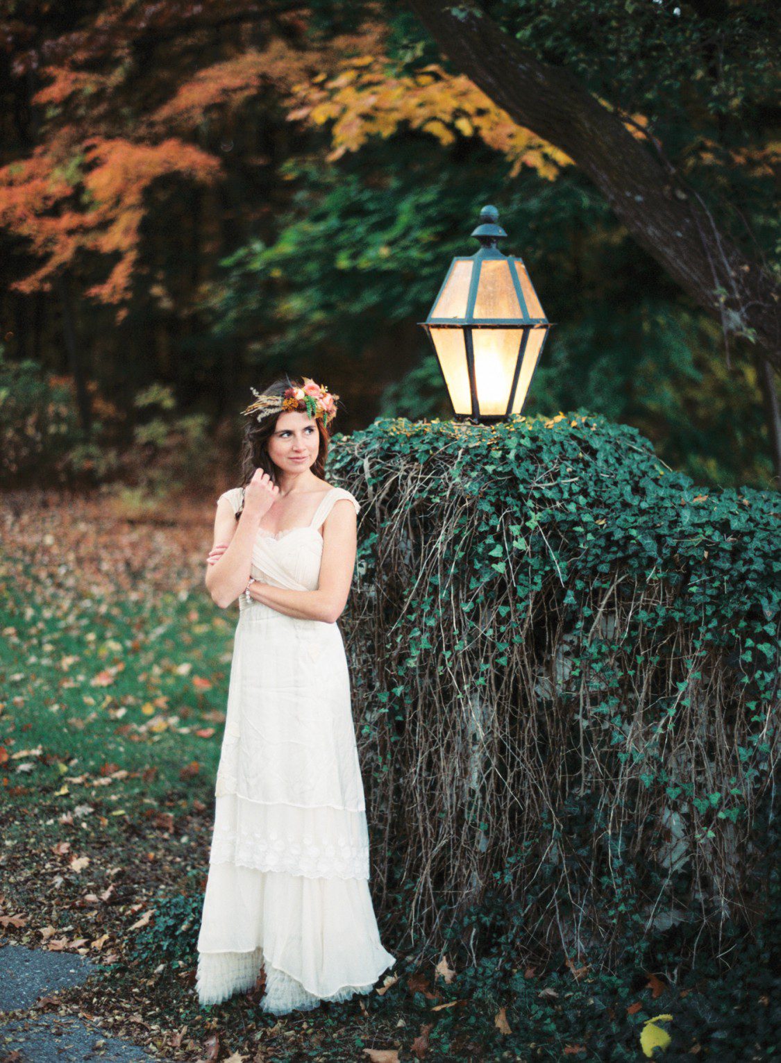 fall bride poses beside ivy fence in northern michigan