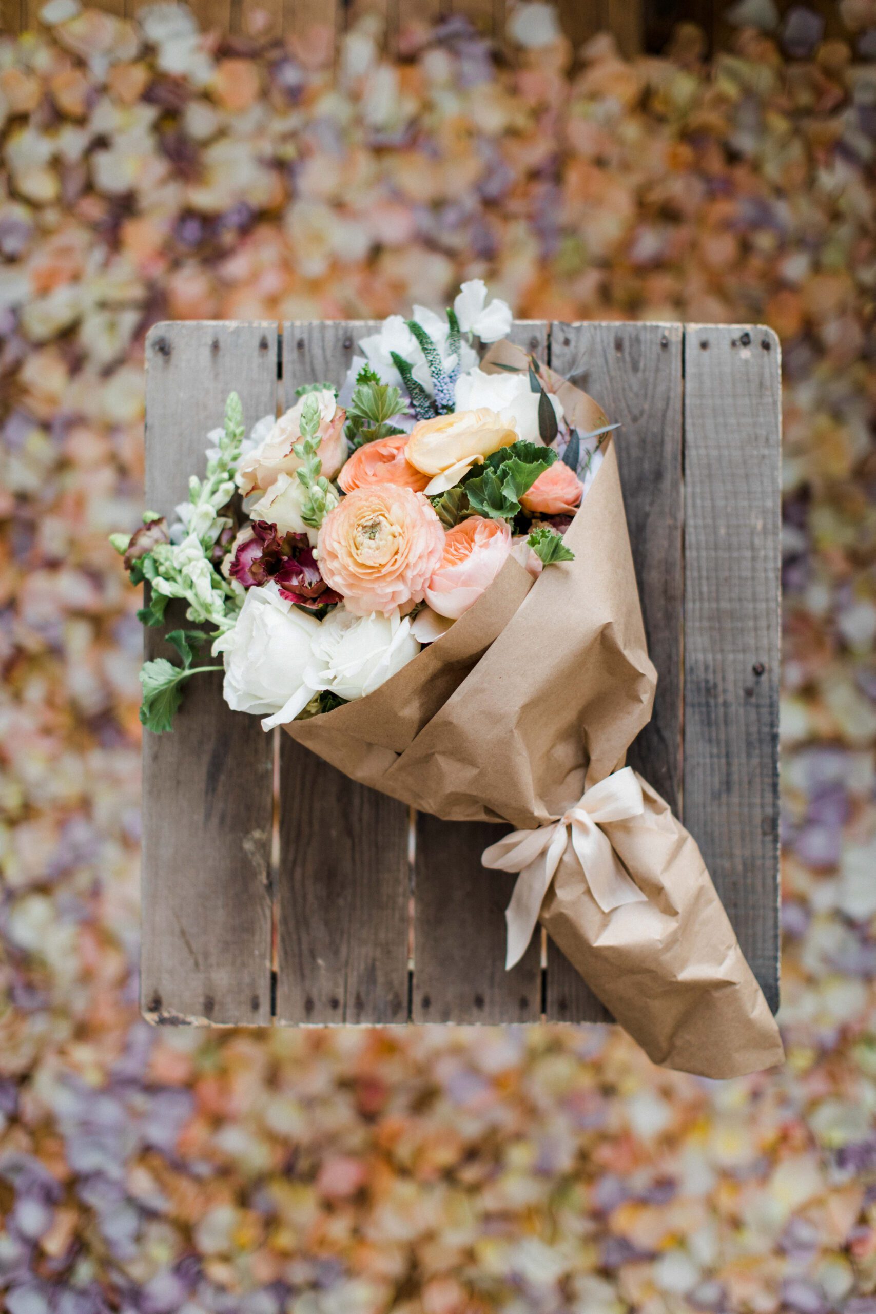 A bouquet of flowers sits atop a wooden stool for business photography