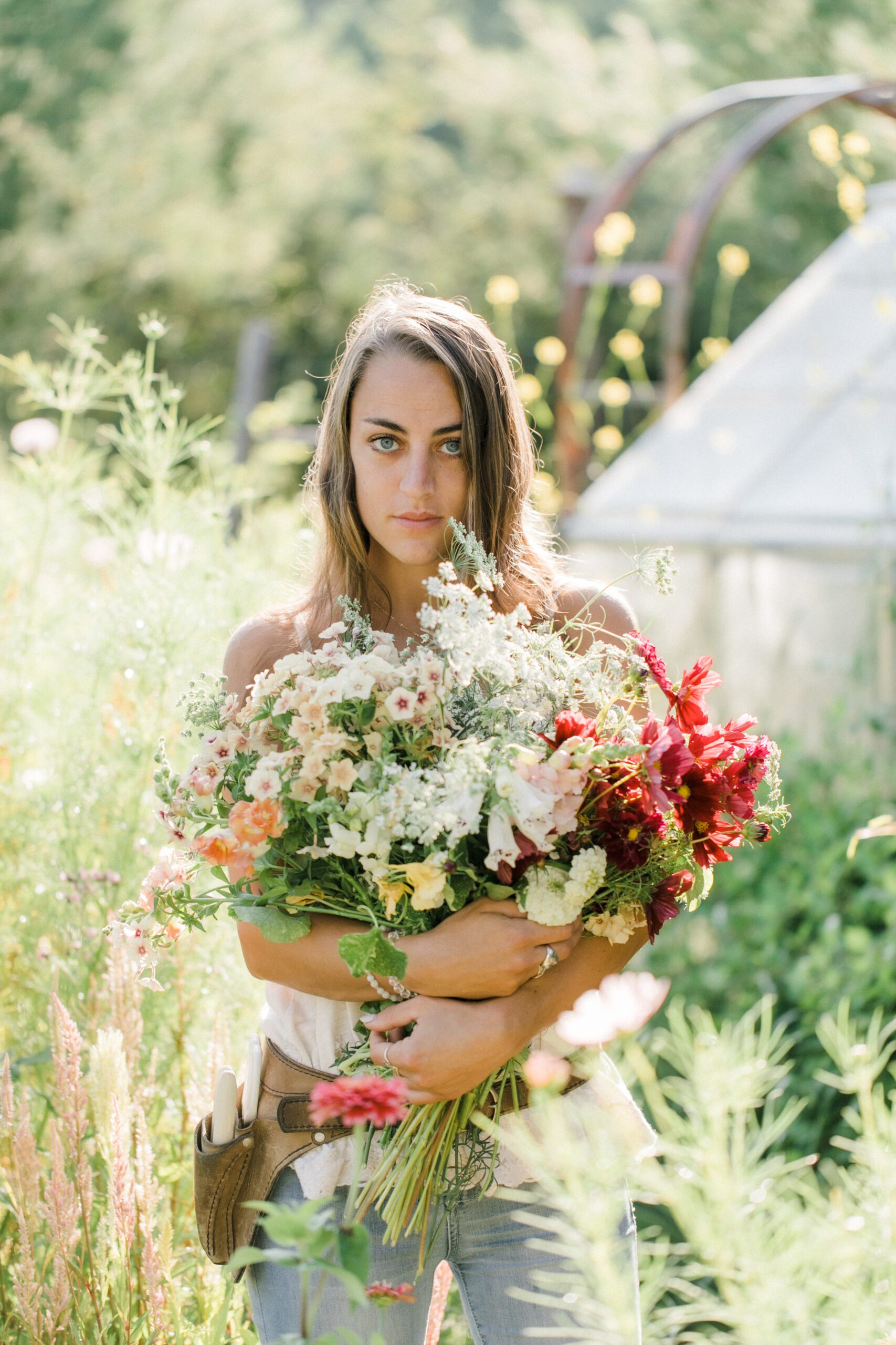 A women poses holding flowers in a garden for individual business photography