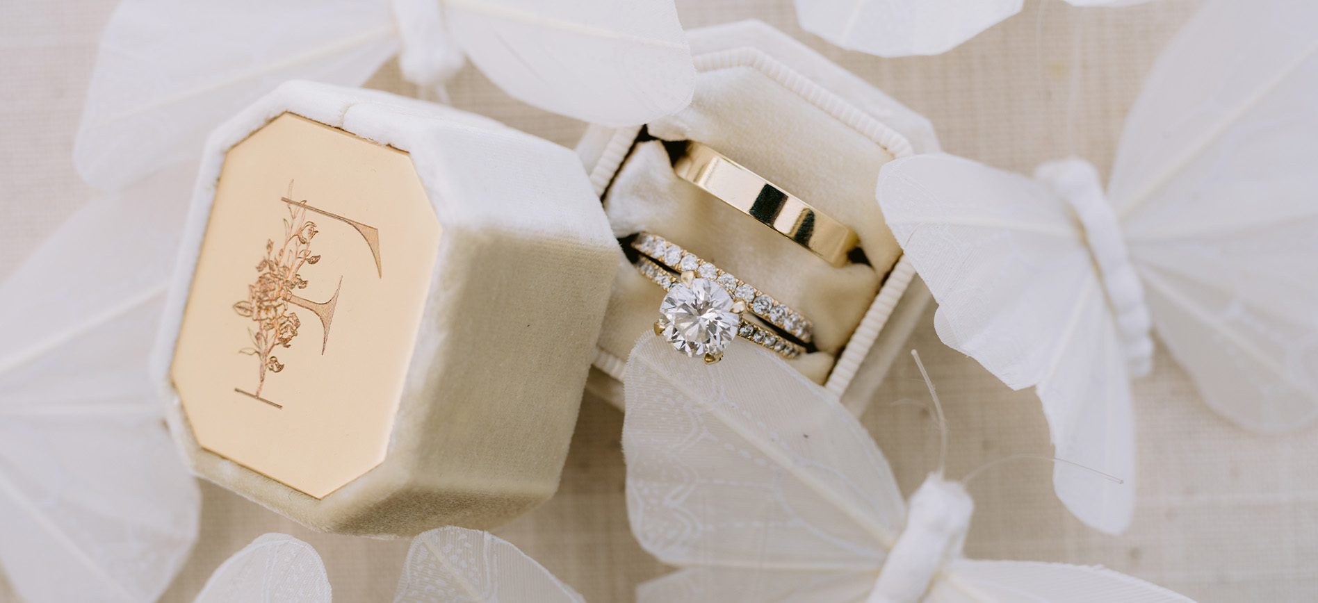 A photograph of wedding rings surrounded by white lace butterflies