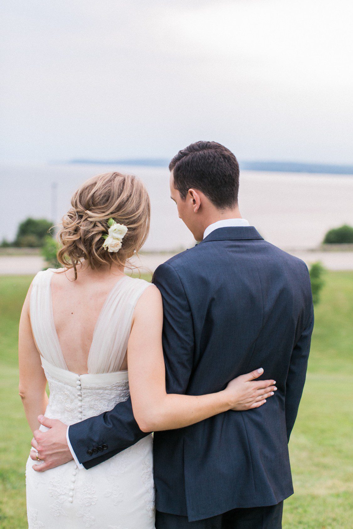 a bride and groom look out over a lake in northern michigan