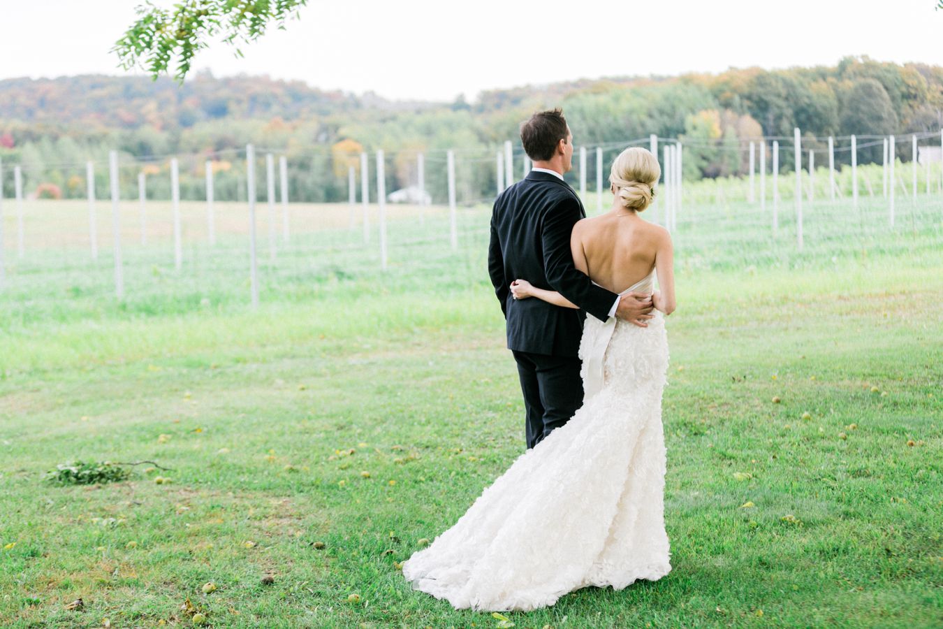 a couple walks beside a vineyard on their wedding day